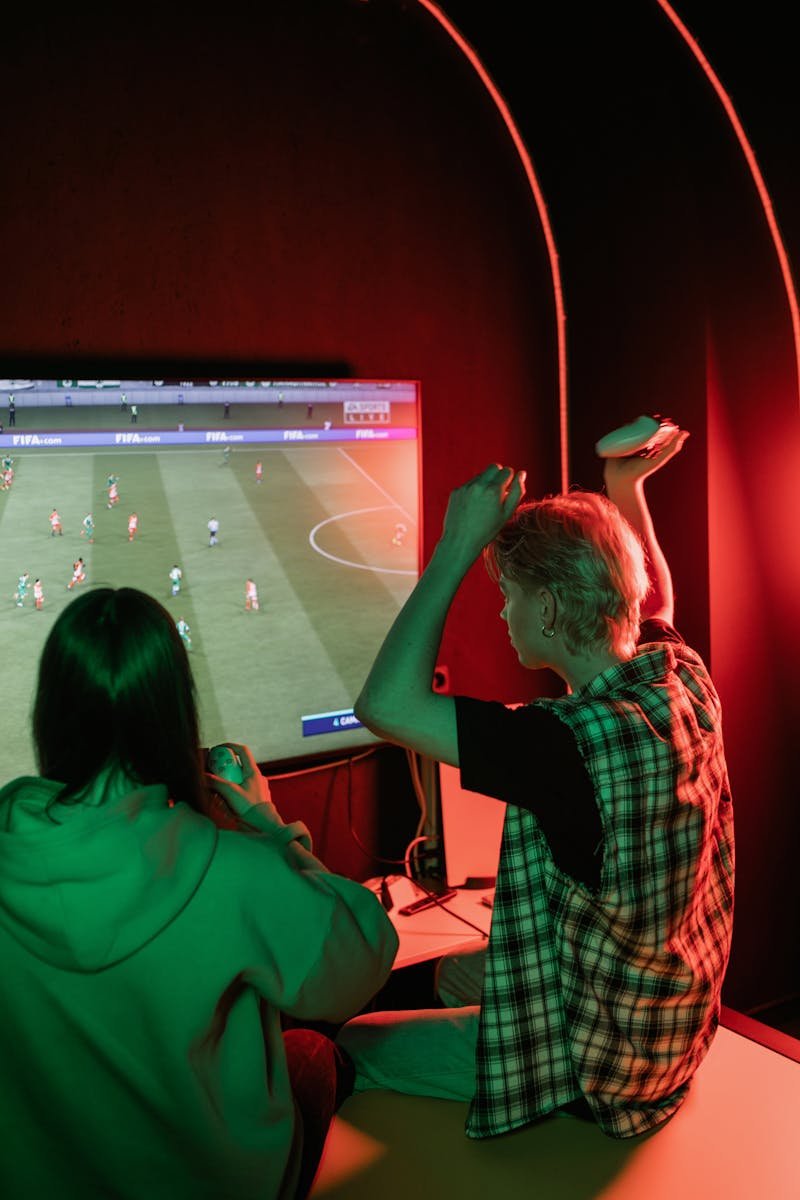 Two teenagers enthusiastically playing video games on a console in a cozy room.