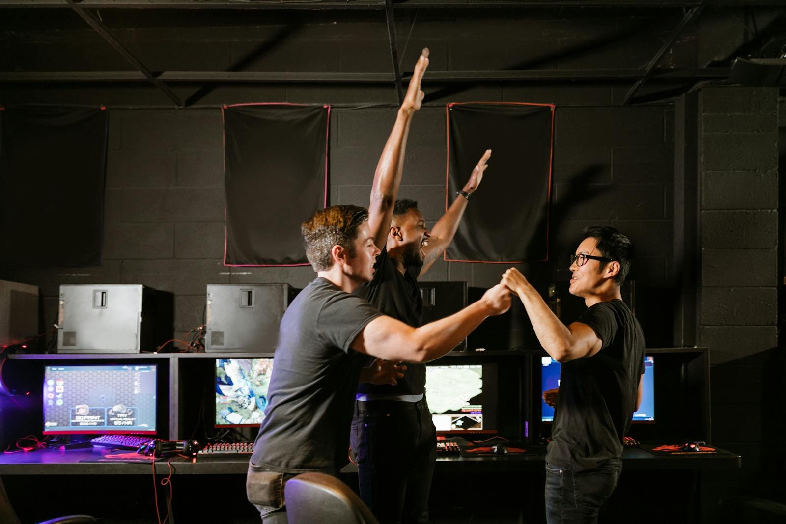 Three excited gamers celebrating their victory in an esports gaming arena, showing teamwork and joy.